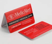 Red wallet card with a MedicAlert Logo showing on the face of the card. The card is on a table.