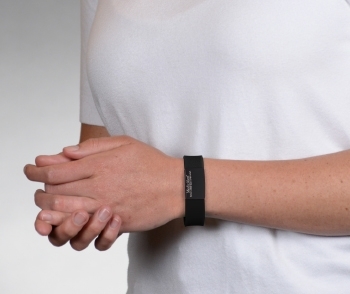 Person wearing on wrist the Performance silicone Medical ID bracelet with a black band and a black colored rectangular emblem
