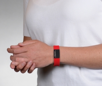 Person wearing on wrist the Performance silicone Medical ID bracelet with a red band and a black colored rectangular emblem