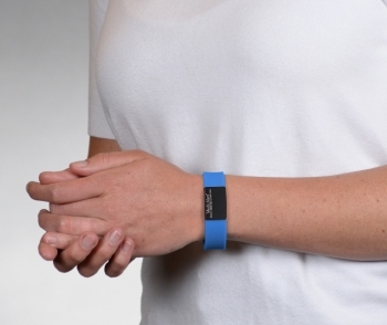 Person wearing on wrist the Performance silicone Medical ID bracelet with a blue band and a black colored rectangular emblem