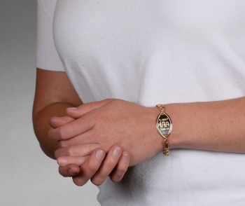 A person wearing a 14 karat gold Santa Rosa medical ID bracelet with oval MedicAlert emblem and logo