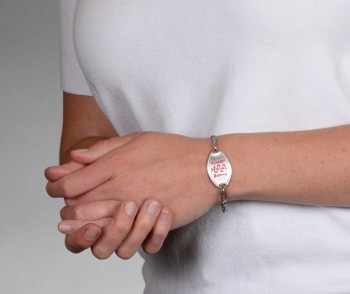 Person wearing classic MedicAlert medical ID bracelet in stainless steel with pink MedicAlert logo on front