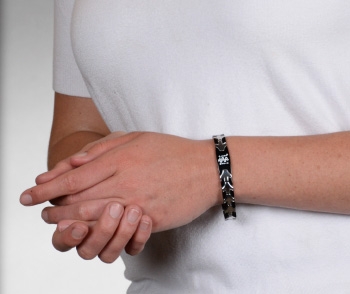Person wearing black and silver medical ID bracelet with MedicAlert emblem and logo
