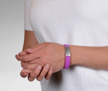 Person wearing a violet silicone medical ID bracelet with rectangle MedicAlert emblem