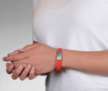 Person wearing a red silicone medical ID bracelet with rectangle MedicAlert emblem 