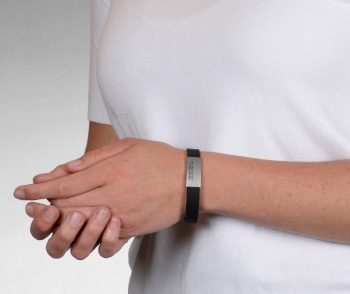 Person wearing black silicone medical ID bracelet with rectangle MedicAlert emblem 