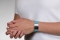 Person wearing a teal flexible fabric medical ID bracelet with oval MedicAlert emblem