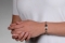 A person wearing a rose gold medical ID Bracelet with rectangular interlocking and heart shaped links, oval MedicAlert emblem in silver